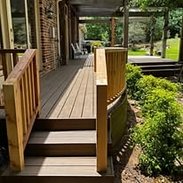 Wood deck with railing and an access ramp beside a brick home