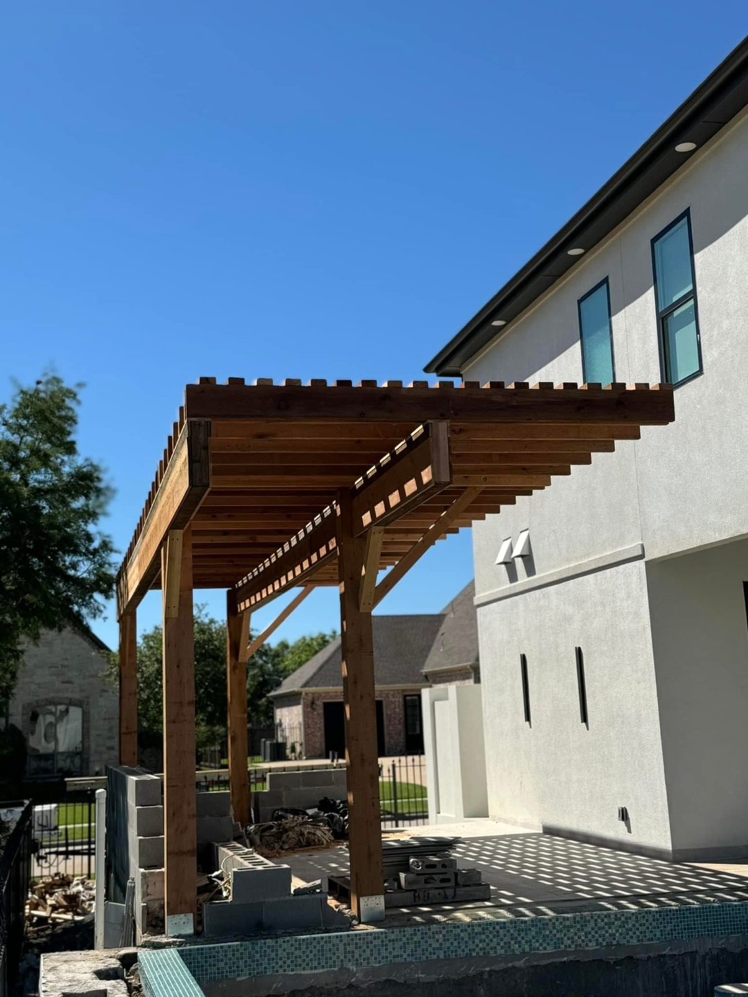 Cedar pergola under construction beside a backyard pool