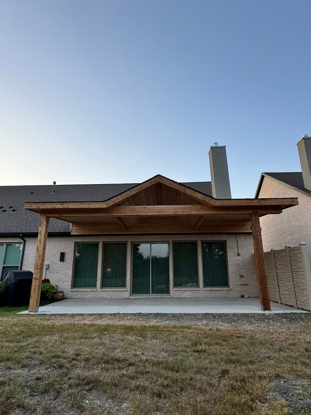 Gable cedar patio cover attached to a home at dusk