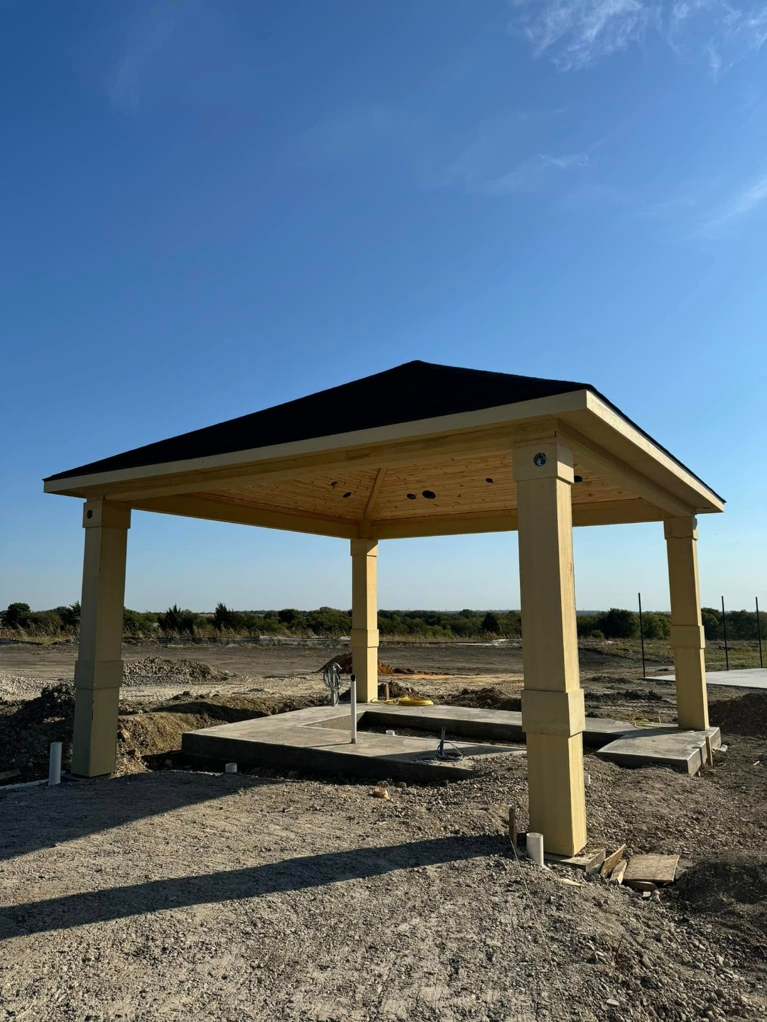 Freestanding hip-roof cedar pavilion on a new construction lot