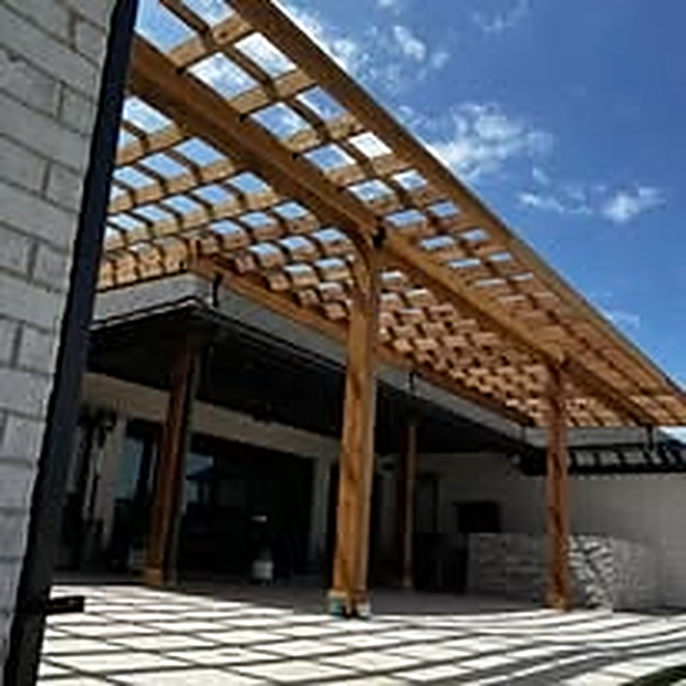 Open-beam cedar pergola casting dramatic shadow patterns on a modern patio