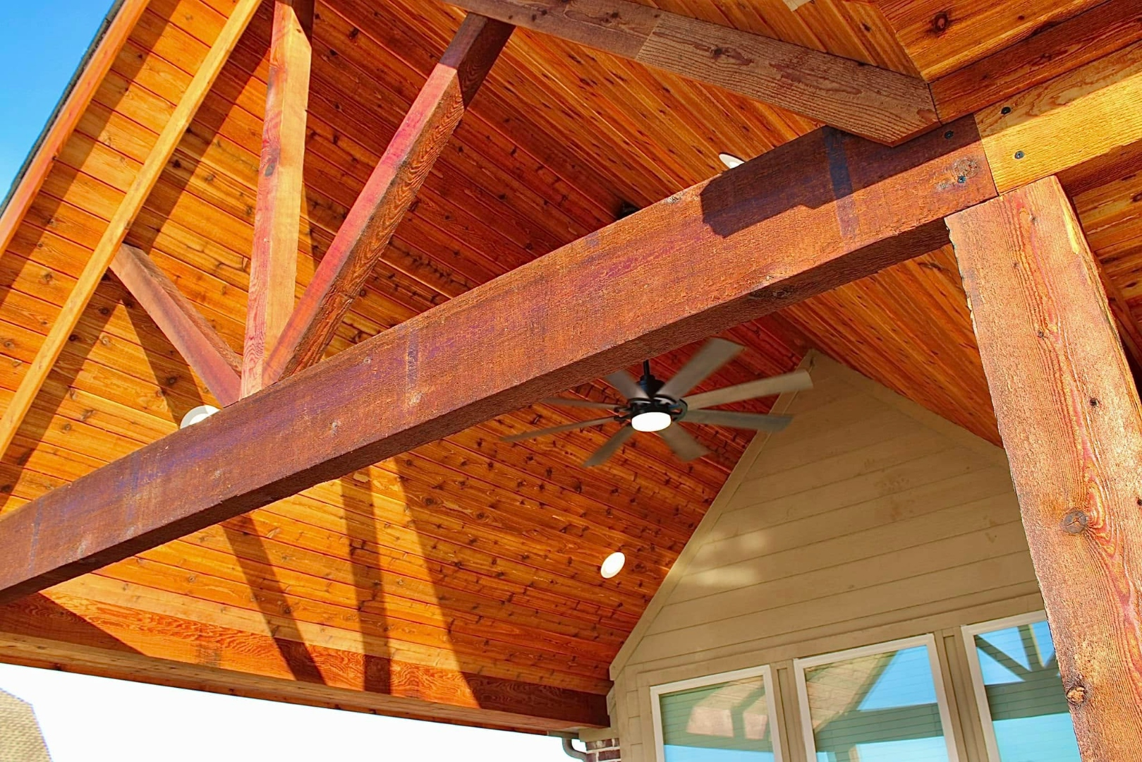 Close-up of a custom stained cedar patio cover roof structure with ceiling fan