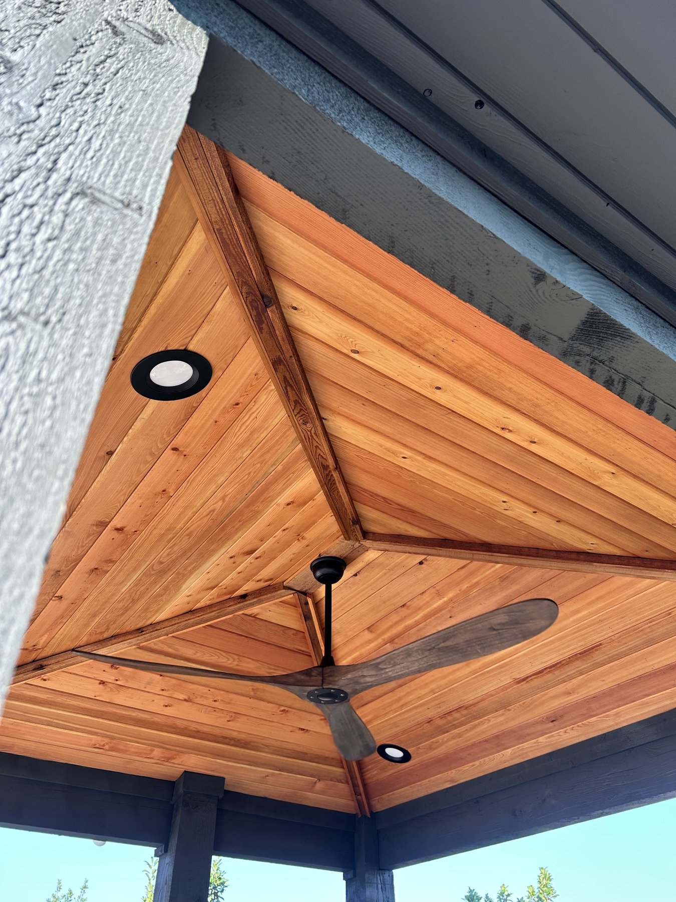 Finished cedar tongue-and-groove patio cover ceiling with recessed lighting and a ceiling fan