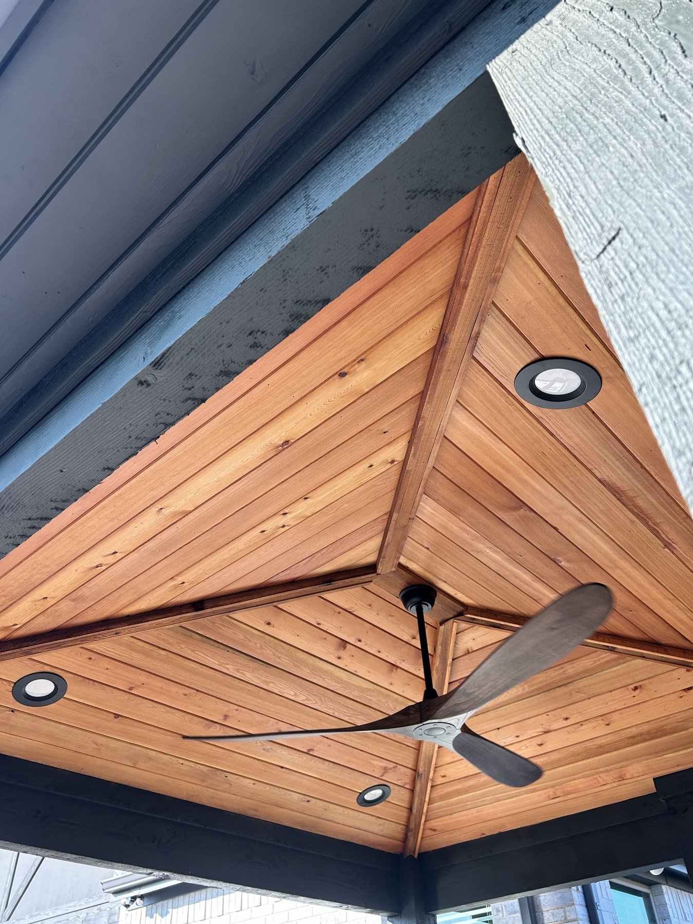 Finished cedar tongue-and-groove patio cover ceiling with recessed lighting and a ceiling fan